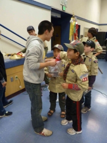 young boy scouts choosing prizes from bag student is holding